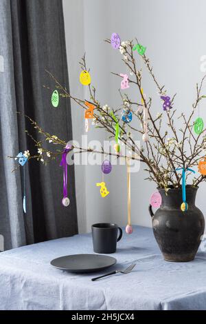 Blooming cherry branches decorated with colorful ribbons with Easter eggs, Happy Easter, table setting Stock Photo
