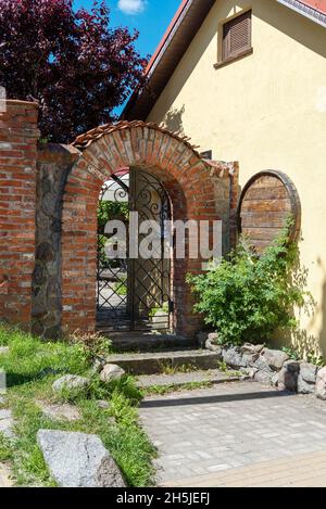 Brick arch with wrought iron grating, entrance in the courtyard of the house. The concept of vintage architecture.