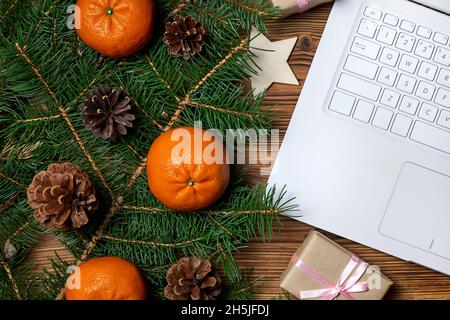 Christmas composition of open notebook, fir branches, pine cones and tangerines on wooden background Stock Photo