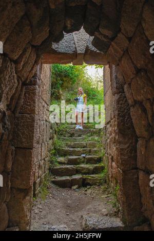 a girl stands in the aisle through the arch on stone steps Stock Photo