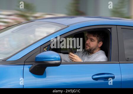 Man looks at the smartphone while driving fast. Dangerous driving. Stock Photo