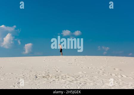 Young sporty man want doing acrobatic exercises on the sand near river Stock Photo