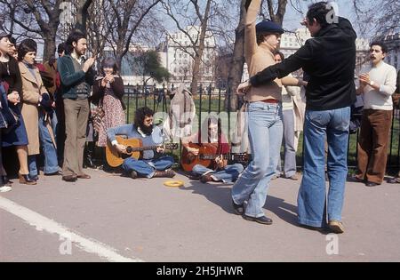 London 1982. A street view of a couple dancing to the music of street musicians sitting on the pavement with a park in the background. Credit Roland Palm. Stock Photo