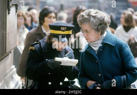 London 1982. A London street view and traffic warden trying to help an elderly lady to find her way. She holds a map and they are both looking at it. Credit Roland Palm. Stock Photo