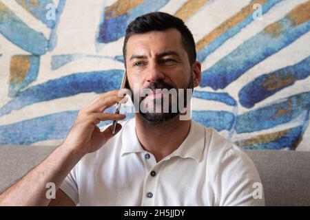 man sitting on the sofa in the hotel room talking on the mobile phone. Stock Photo