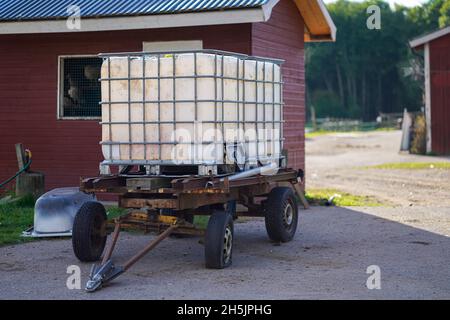 Old plastic water tank on the rusty trailer at the animal farm Stock Photo