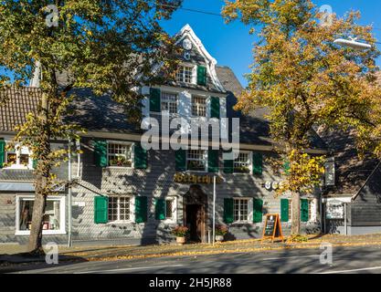 Germany, Haan, Bergisches Land, Niederbergisches Land, Niederberg, Rhineland, North Rhine-Westphalia, NRW, Becherhus in the Kaiserstrasse, half-timbered house with slate facade, green shutters, Bergisches Baroque, gastronomy, restaurant, autumnal trees, autumn colouring, fall foliage Stock Photo