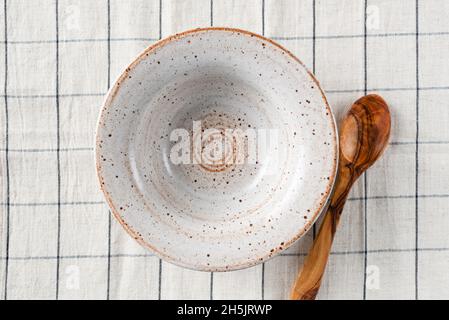 Empty soup bowl and wooden spoon on linen table textile Stock Photo