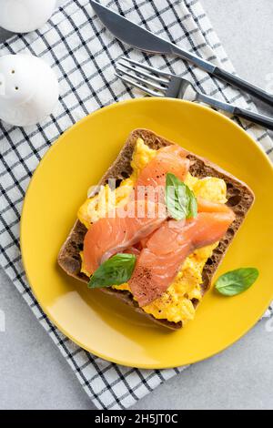 Toast with salmon and scrambled eggs on a yellow plate, top view. Breakfast food Stock Photo