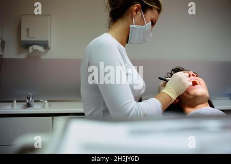 Dentist working on patient's teeth inside dental office; Germany Stock Photo