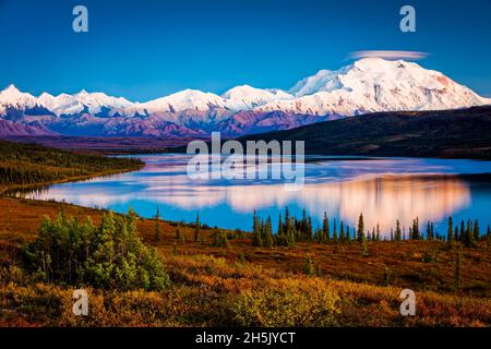 Sunset glow on Mount Denali (McKinley) reflects on Wonder Lake with pastel sky, Denali National Park and Preserve in autumn, Interior Alaska Stock Photo