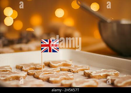 British holiday and Christmas baking concept. Union Jack flag of Great Britain and gingerbread men biscuits in the kitchen in England Stock Photo