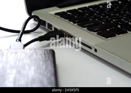 External hard drive connect to laptop computer on the white background. Stock Photo
