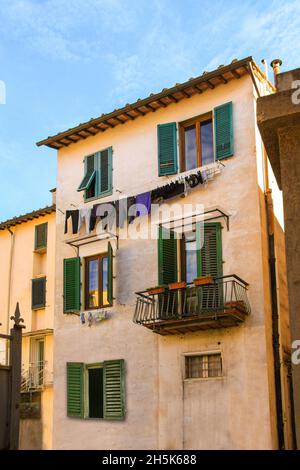 Old mediterranean house with laundry clothes hanged and drying in a line. Blue sky background. Stock Photo