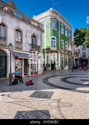 Lagos, Algarve, Portugal - November 10 2021: Luis de Camoes Square with mature gentleman performing with musical instrument for the tourists enjoying Stock Photo