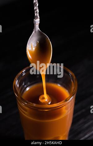 Homemade salted caramel sauce in a jar on a dark background. copy space text Stock Photo