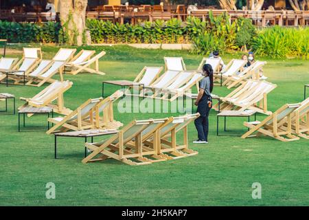 KANCHANABURI, THAILAND-FEBRUARY 3,2021 : Unidentified waitress wears face mask to prevent COVID-19 stand by to serve customers among many deck chairs Stock Photo