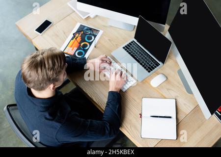 Overhead view of programmer using computers near smartphone and eyeglasses on table Stock Photo