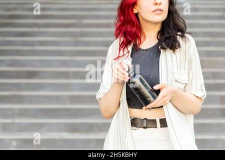 Woman holding reusable stainless steel water bottle over gray background with copy space Stock Photo