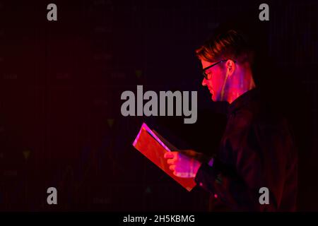 Side view of programmer holding paper folder isolated on black Stock Photo