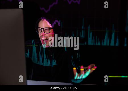 Angry hacker with charts reflection using computer on black background Stock Photo