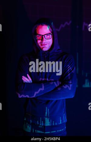 Hacker in eyeglasses with charts reflection looking at camera on black background Stock Photo