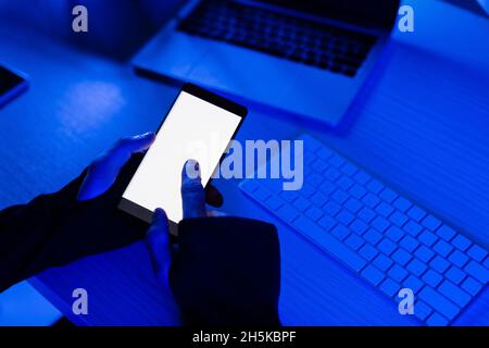 Cropped view of programmer using smartphone near laptop and computer keyboard on table Stock Photo