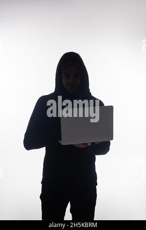 Hacker holding laptop and looking at camera isolated on grey Stock Photo