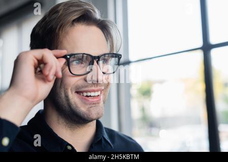 Cheerful programmer in eyeglasses looking away in office Stock Photo