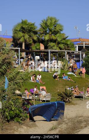 Tourists and local relaxing on the grass in front of a chiringuito on Los Lances beach. Tarifa, Costa de la Luz, Cadiz Province, Andalucia, spain Stock Photo