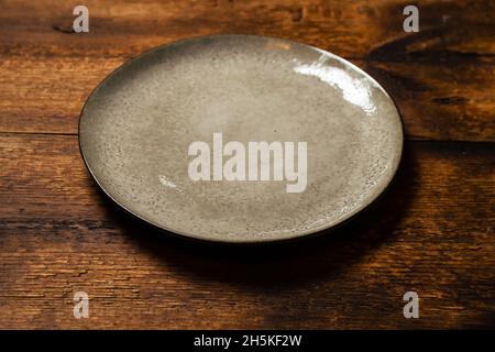 empty clay plate on dark wooden background Stock Photo