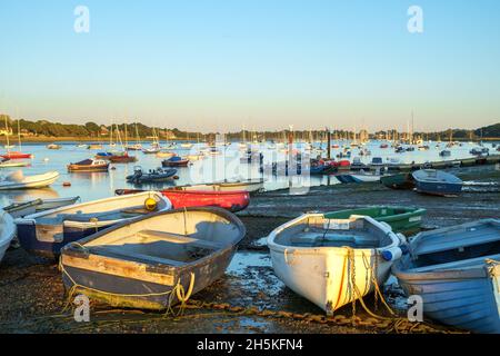 Rowing boats and yachts at Itchenor, Chichester Harbour, in the evening light at low tide. Stock Photo