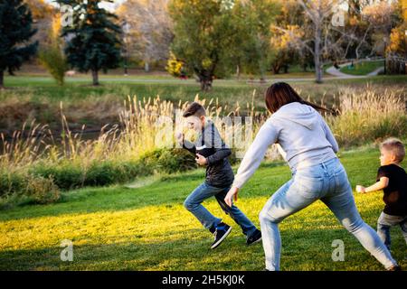 Mother chasing her son in a game of football on a beautiful autumn day in a city park; St. Alberta, Alberta, Canada Stock Photo