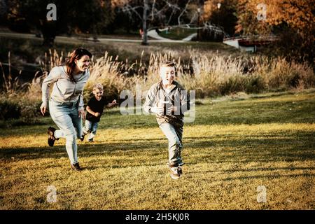 Mother chasing her son in a game of football on a beautiful autumn day in a city park; St. Alberta, Alberta, Canada Stock Photo