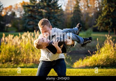 Father playing with his young son in a park in autumn; St. Albert, Alberta, Canada Stock Photo