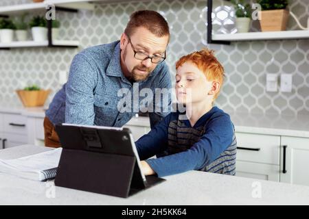Father helping son with homework in the home kitchen; Edmonton, Alberta, Canada Stock Photo
