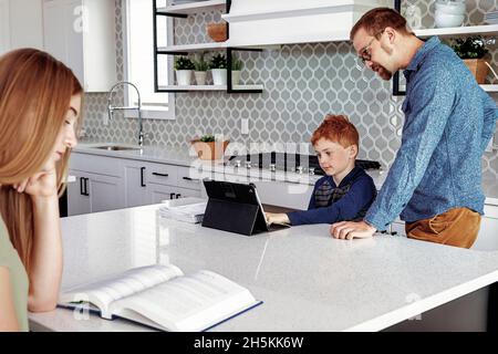 Father helping son with homework in the home kitchen; Edmonton, Alberta, Canada Stock Photo
