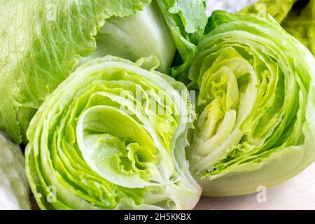 Fresh green iceberg lettuce salad leaves cut on light background on the table in the kitchen. Stock Photo