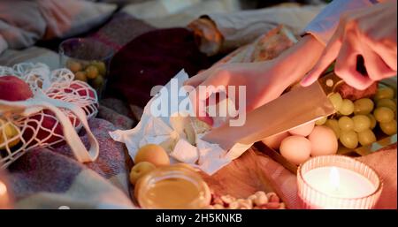 A woman is cutting cheese during a night picnic