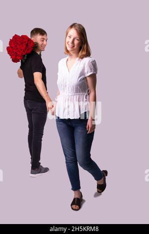 Full-length photo of two pretty people, courier man holding the beautiful bouquet of flowers and lookin at the woman, she is smiling and touches his Stock Photo