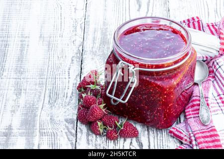 Raspberry  jam in glass jar on white wooden table Stock Photo