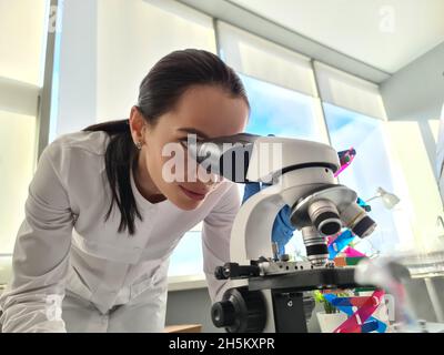 Female scientist chemist looking through microscope in laboratory Stock Photo