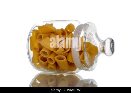 Bright yellow uncooked cannelloni pasta in a glass jar, close-up, isolated on white. Stock Photo
