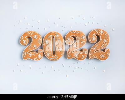 Gingerbread cookies in the form of numbers, gingerbread New Year 2022 on blue background . Top view. Flat lay