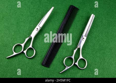 Hairdressing shears with scissors and comb on a green felt table cover Stock Photo