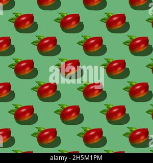Whole ripe red Palmer mangoes cast shadow on a green background. Seamless pattern of tropical juicy mango. Hard light shot texture of fresh mangoes. Stock Photo