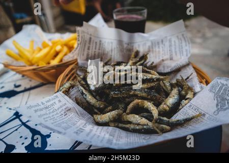 Fried blue fish with french fries served on the table in the town of Primosten, Croatia, popular tourist destination Stock Photo