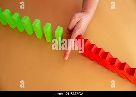 Close up business woman hand stopping wooden blocks from falling. Concept of risk and crisis management in business life. Stock Photo