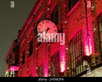 Colourful view at night of the clock on the wall of the Market Hall in Camden London Stock Photo