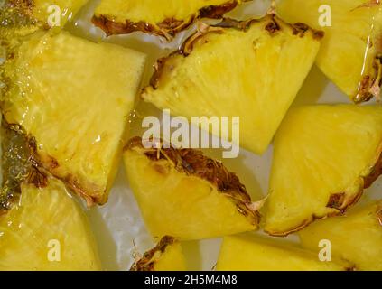Close-up fresh slices of yellow pineapple on white background. Slices of pineapple in sparkling water on white background, close-up. Horizontal image. Stock Photo